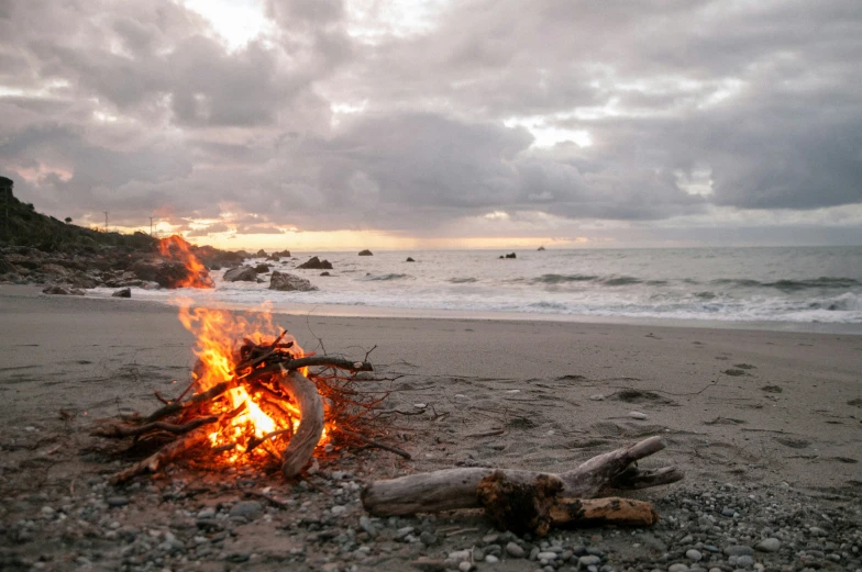 a fire sits in the middle of a beach