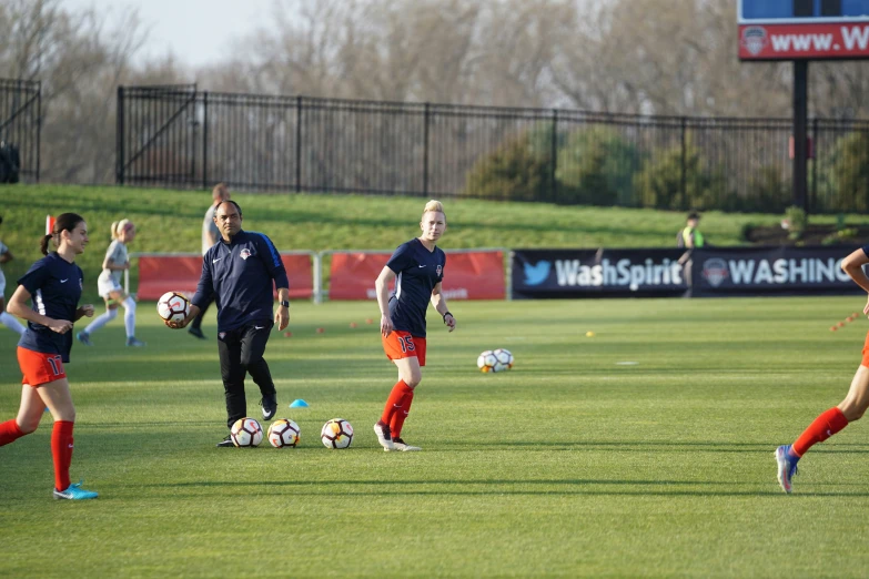 four soccer players walk on the field with their balls