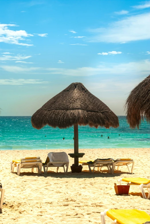a group of chairs sitting on a beach under a thatched umbrella