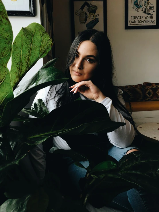 a woman is sitting with a plant and posing for the camera