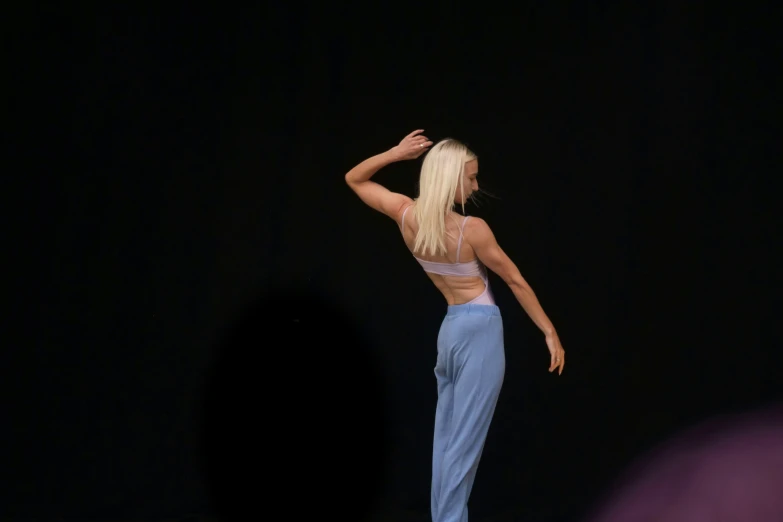 the blonde woman stands on a stage in pants