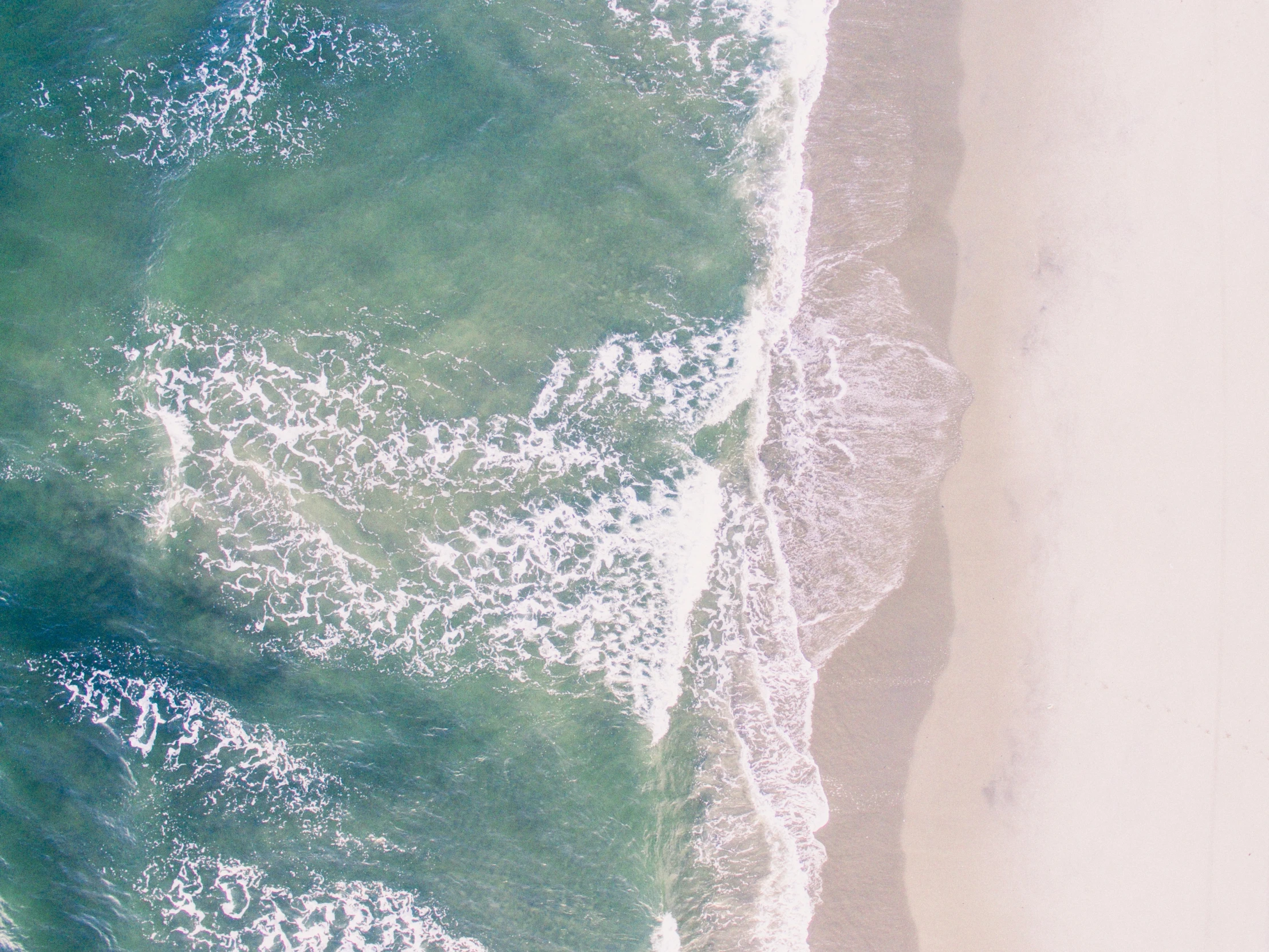 an aerial view of water and sandy beach from above