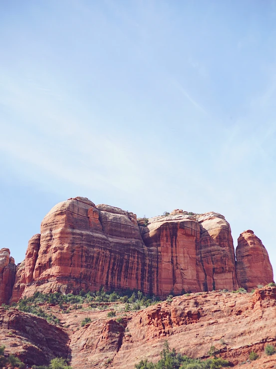 a tall rock formation next to trees and bushes