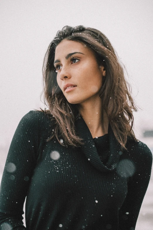 woman in snow covered black outfit looking back to camera