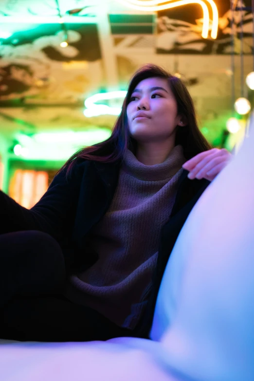 a woman sitting on the floor in a room with lights on