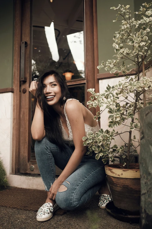 the woman is smiling and leaning up on a window sill