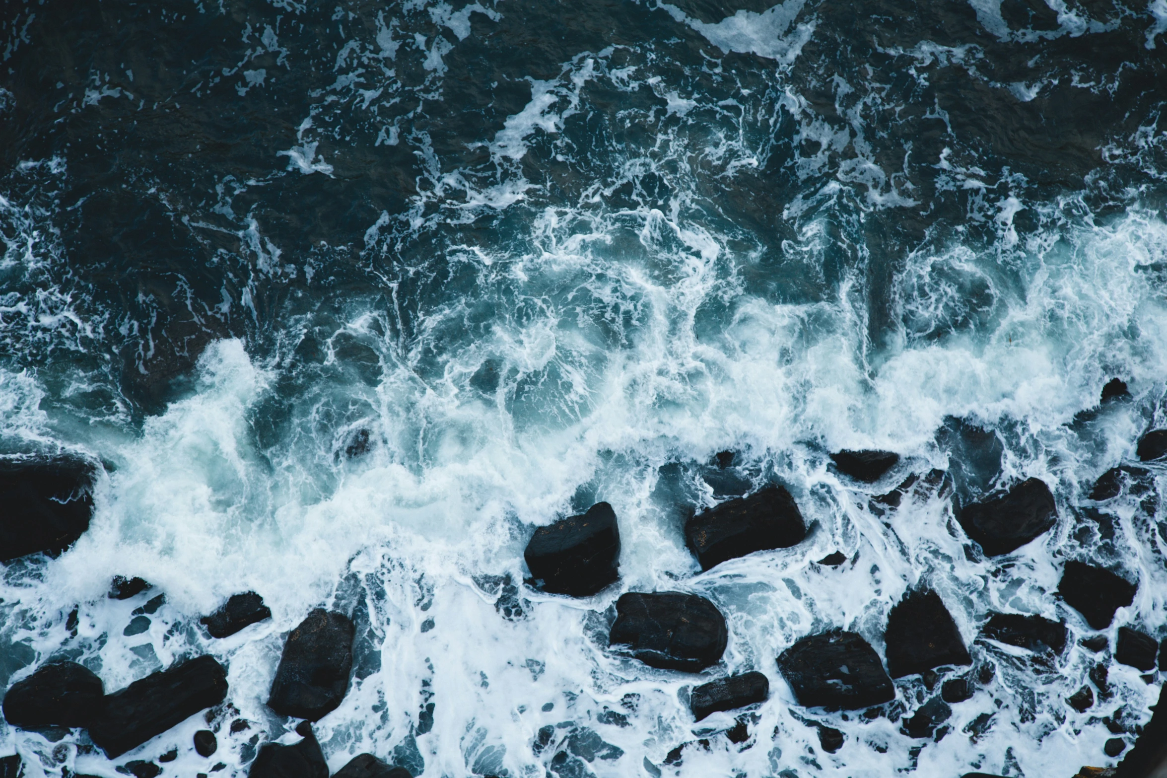 waves and rocky shoreline in the water from above