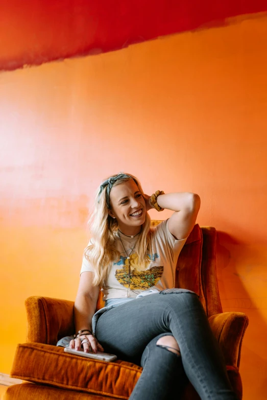 a woman in a white t - shirt sits on an orange chair