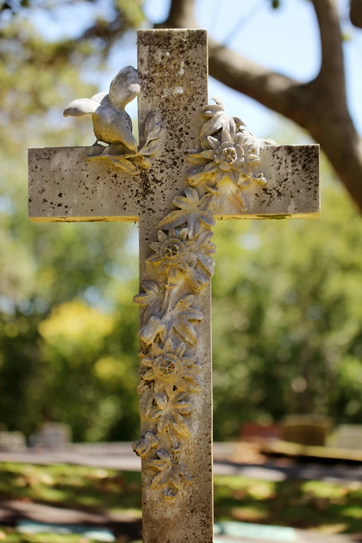 the cross is made of cement and is adorned with flowers