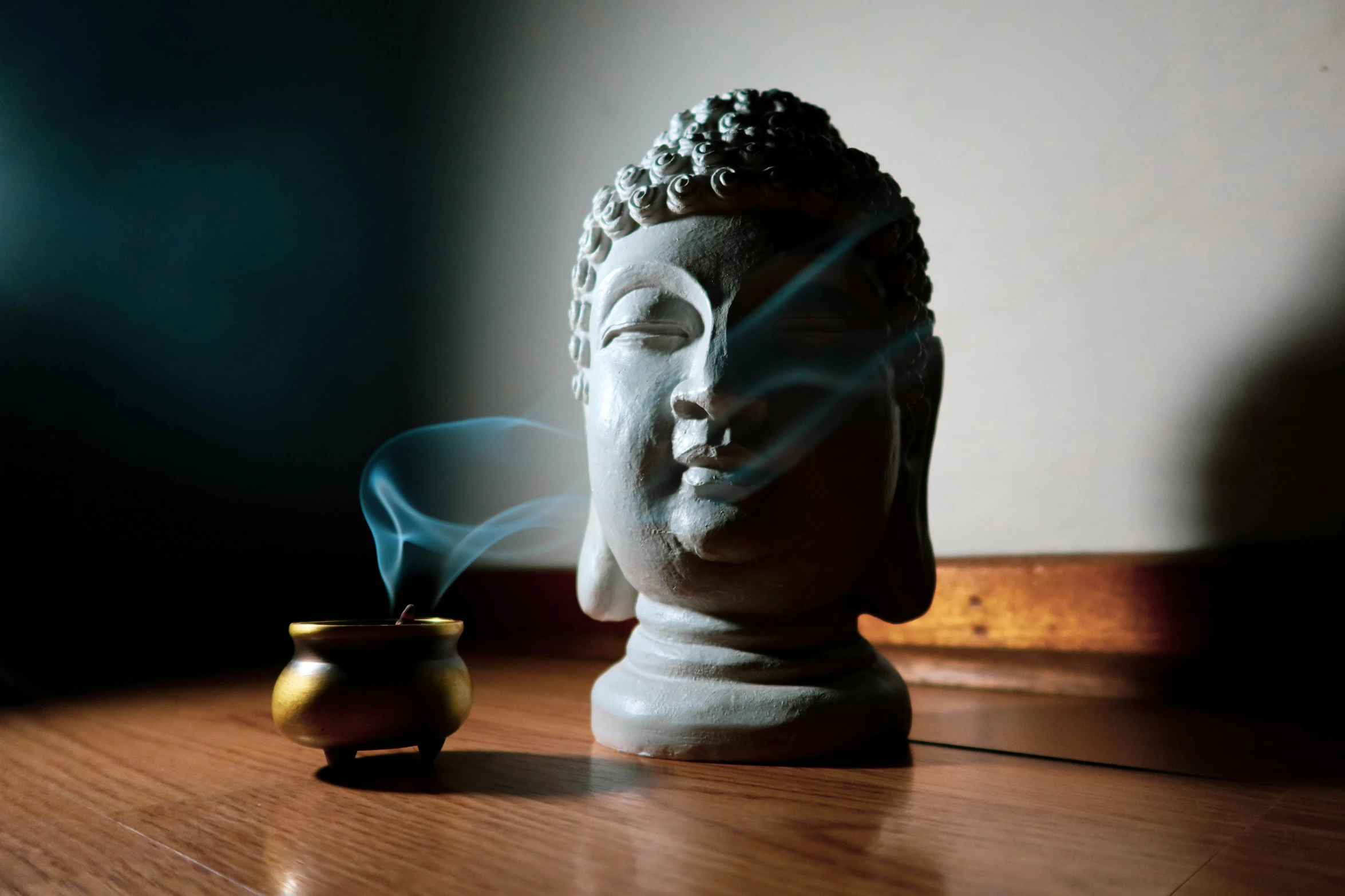 buddha head next to smoke in a vase on table