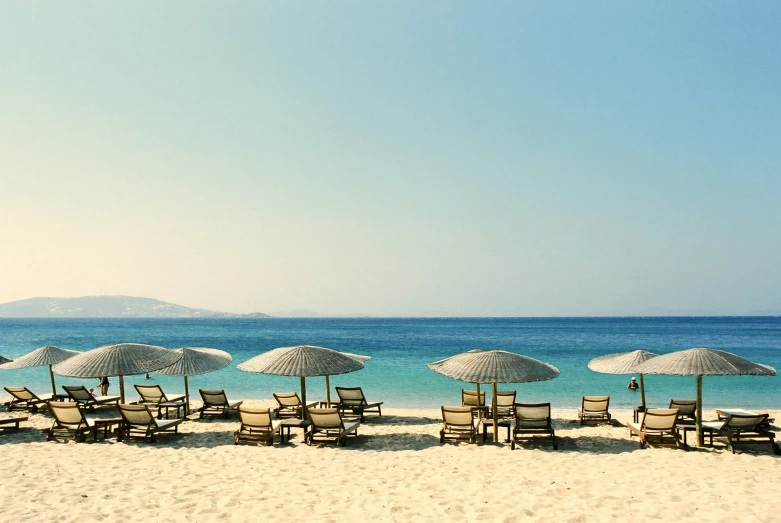 a group of empty beach chairs and umbrellas in the sand