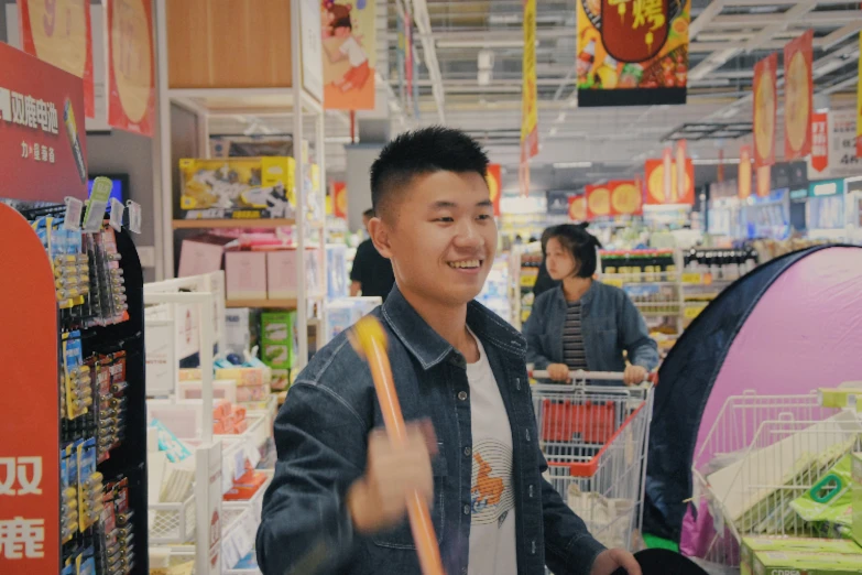 asian man in supermarket grocery cart with handbag giving the thumbs up