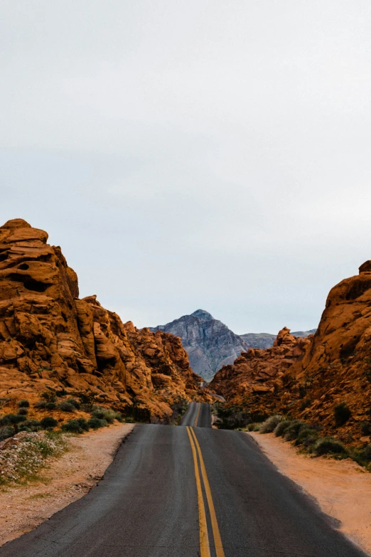 a paved road going through some hills with a sky background