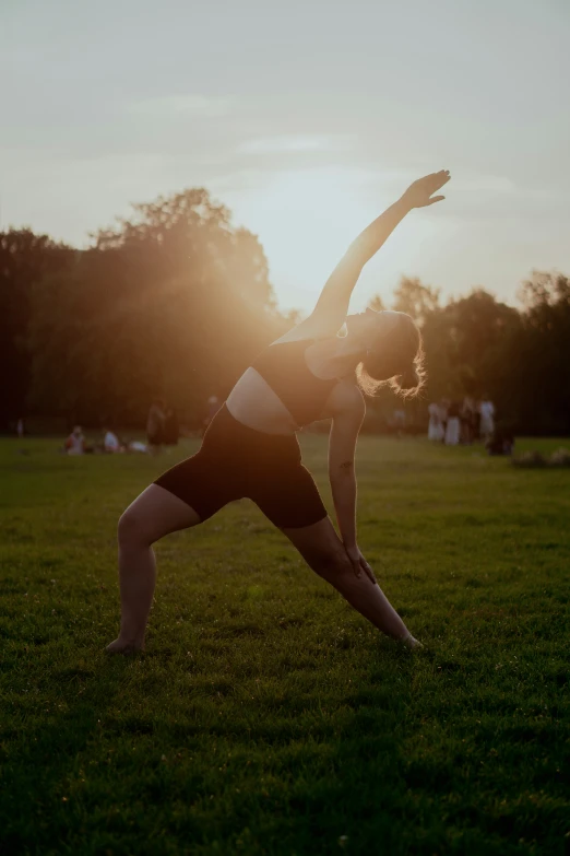 woman standing in a yoga pose in an open park