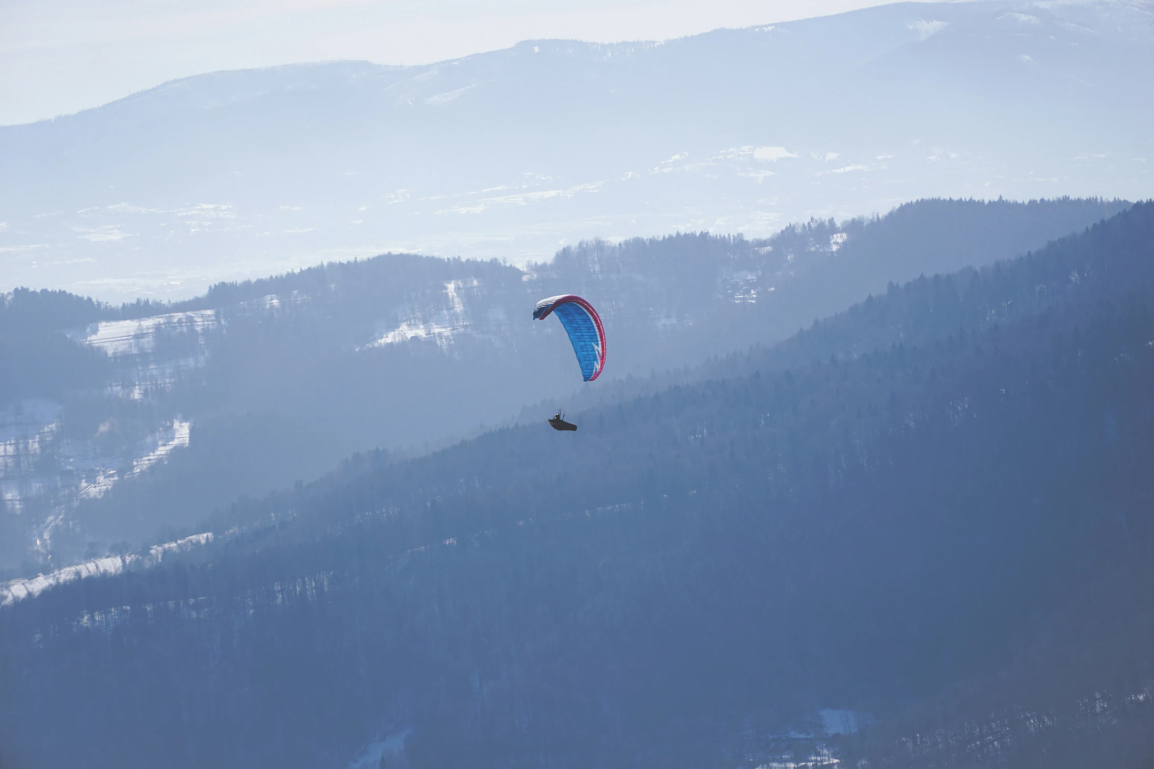 two people para - gliding along a mountain side