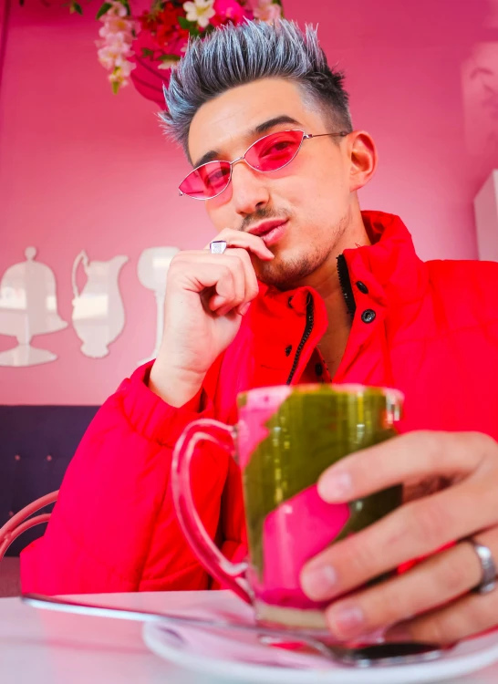 a young man with grey hair and red glasses holding a coffee cup