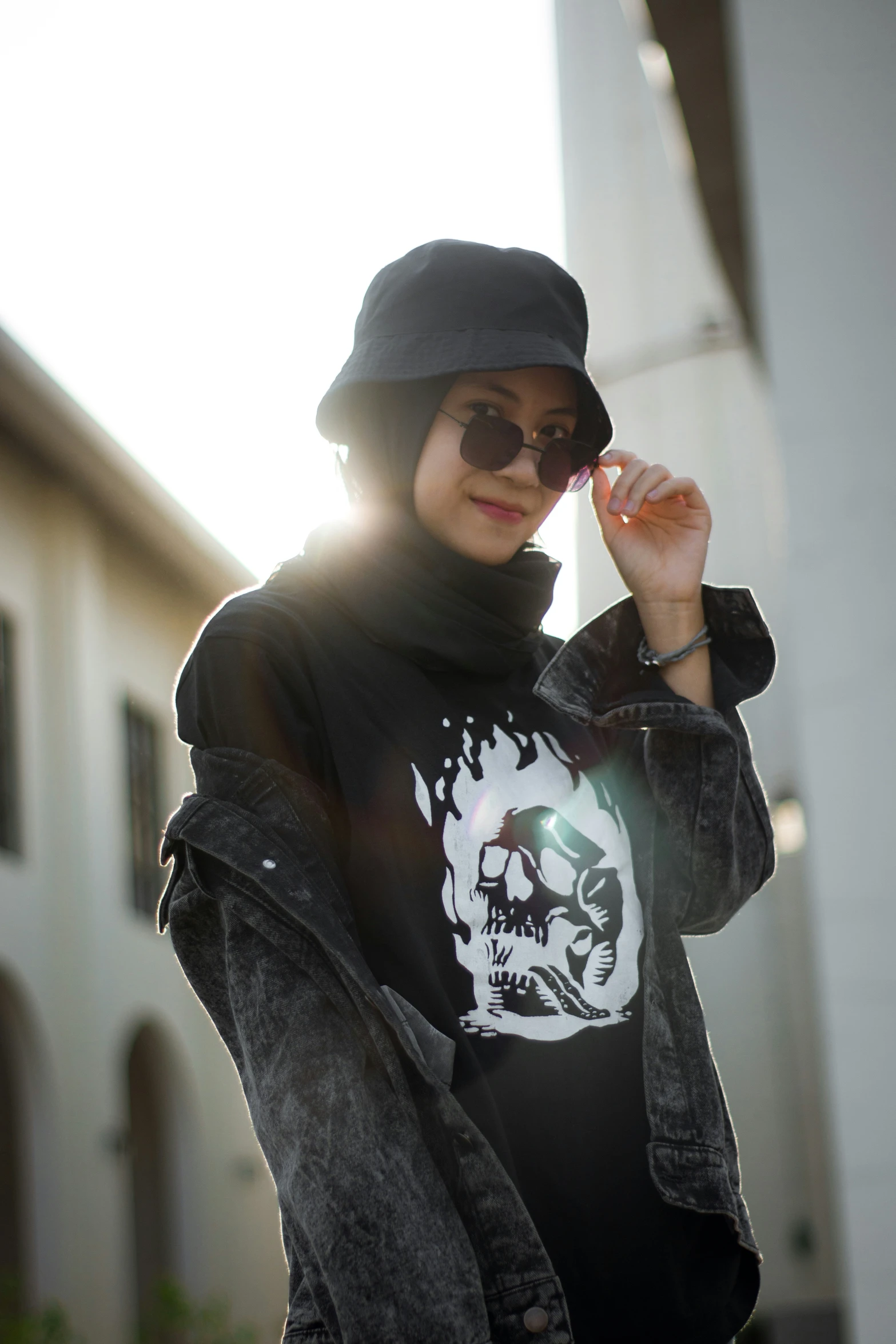 a woman is posing outside, wearing a black hat