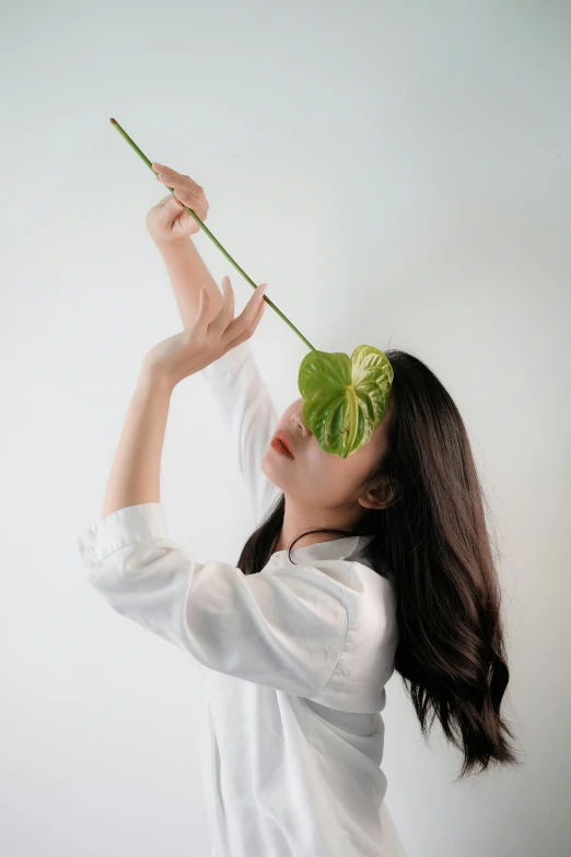 the girl is posing with a large leaf on her head