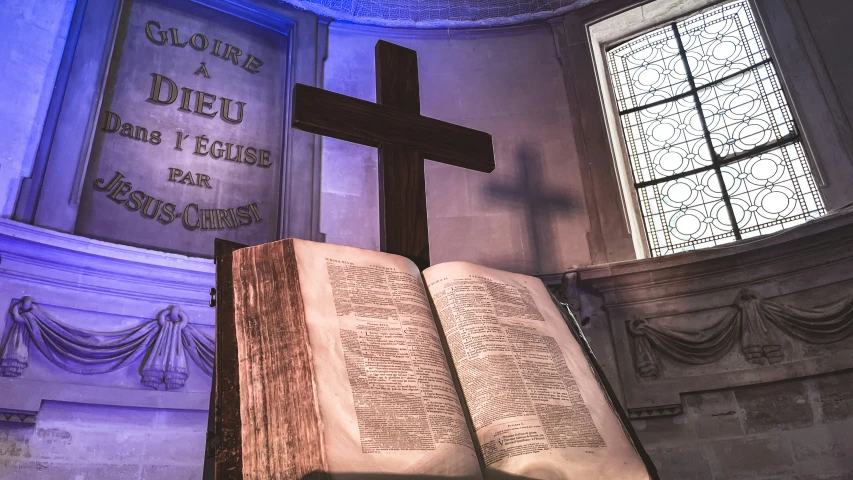 an old book is sitting in front of a cross