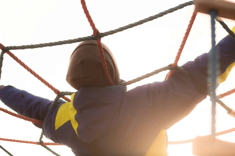 a person with a hat and a hoodie climbing on ropes