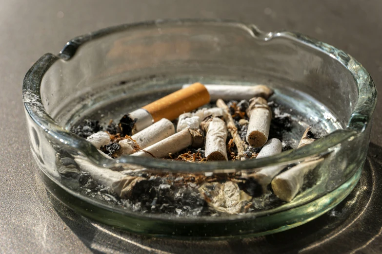 a ashtray full of cigarettes is inside of a glass bowl
