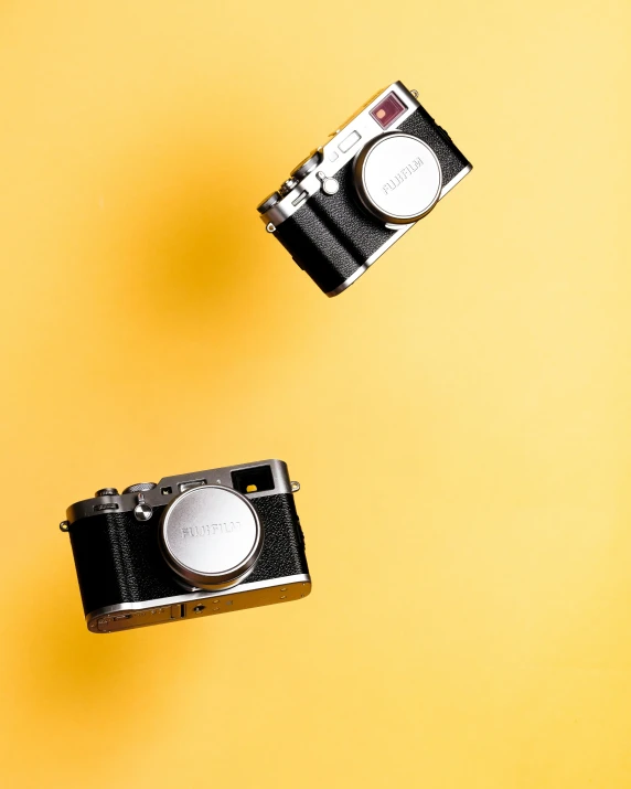 two old fashioned cameras against a yellow background