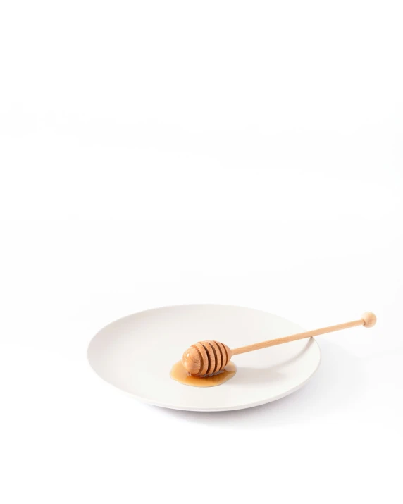 a white plate with a honeycomb and wooden spoon