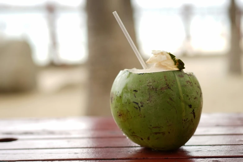 a close up of an orange and green cocktail with a straw