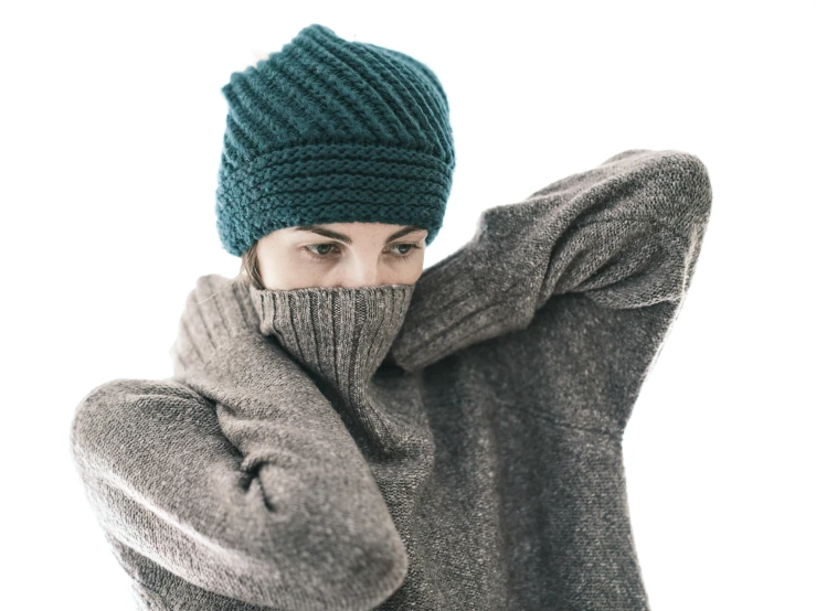 a man wearing a knitted hat is covering his face