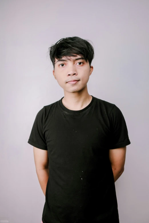 an asian man posing for a pograph in a black t - shirt
