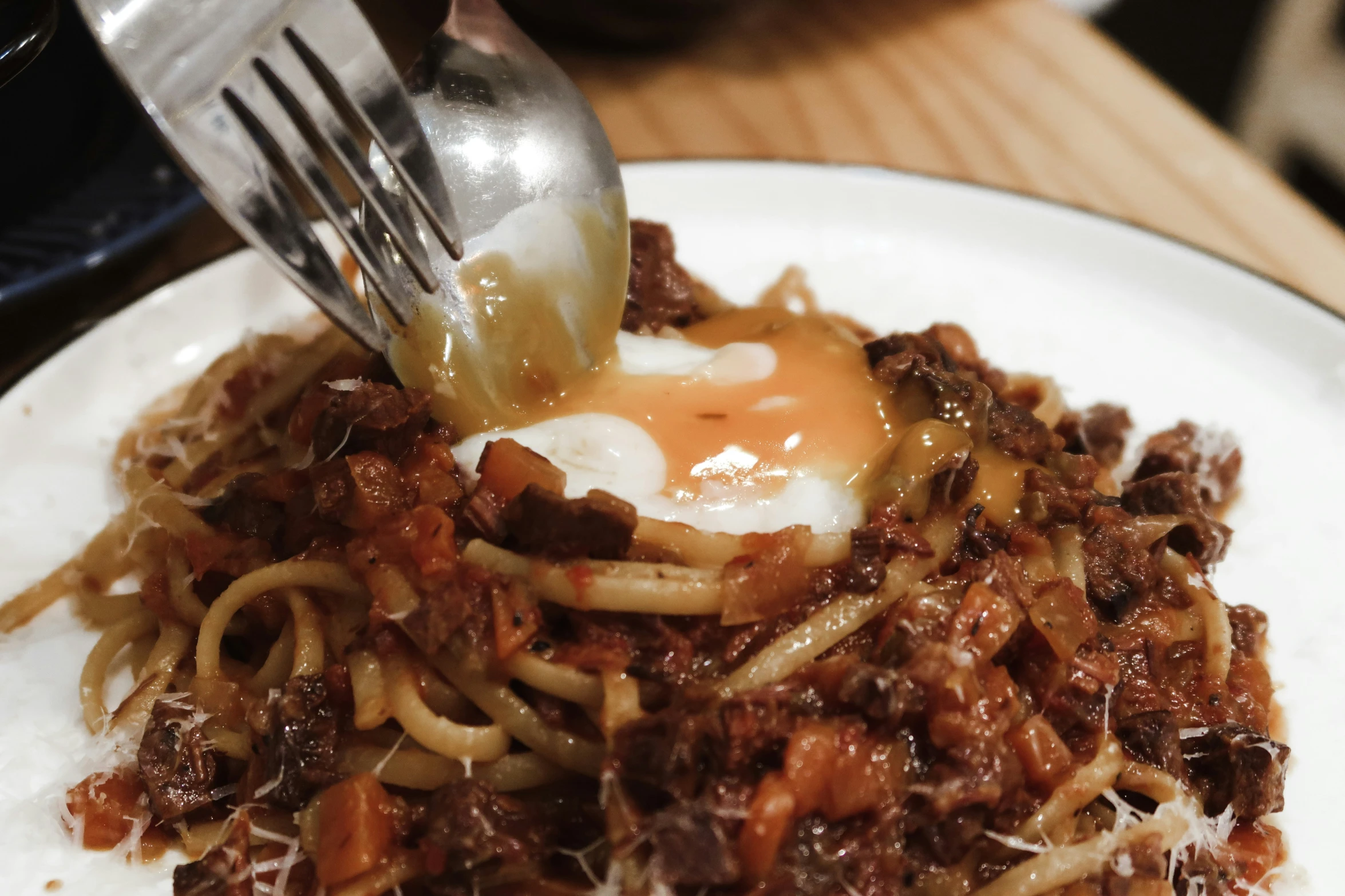 a fork lifting spaghetti out of a white plate with a sauce