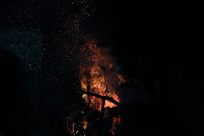 bonfire lit with fire and confetti being blown by wind