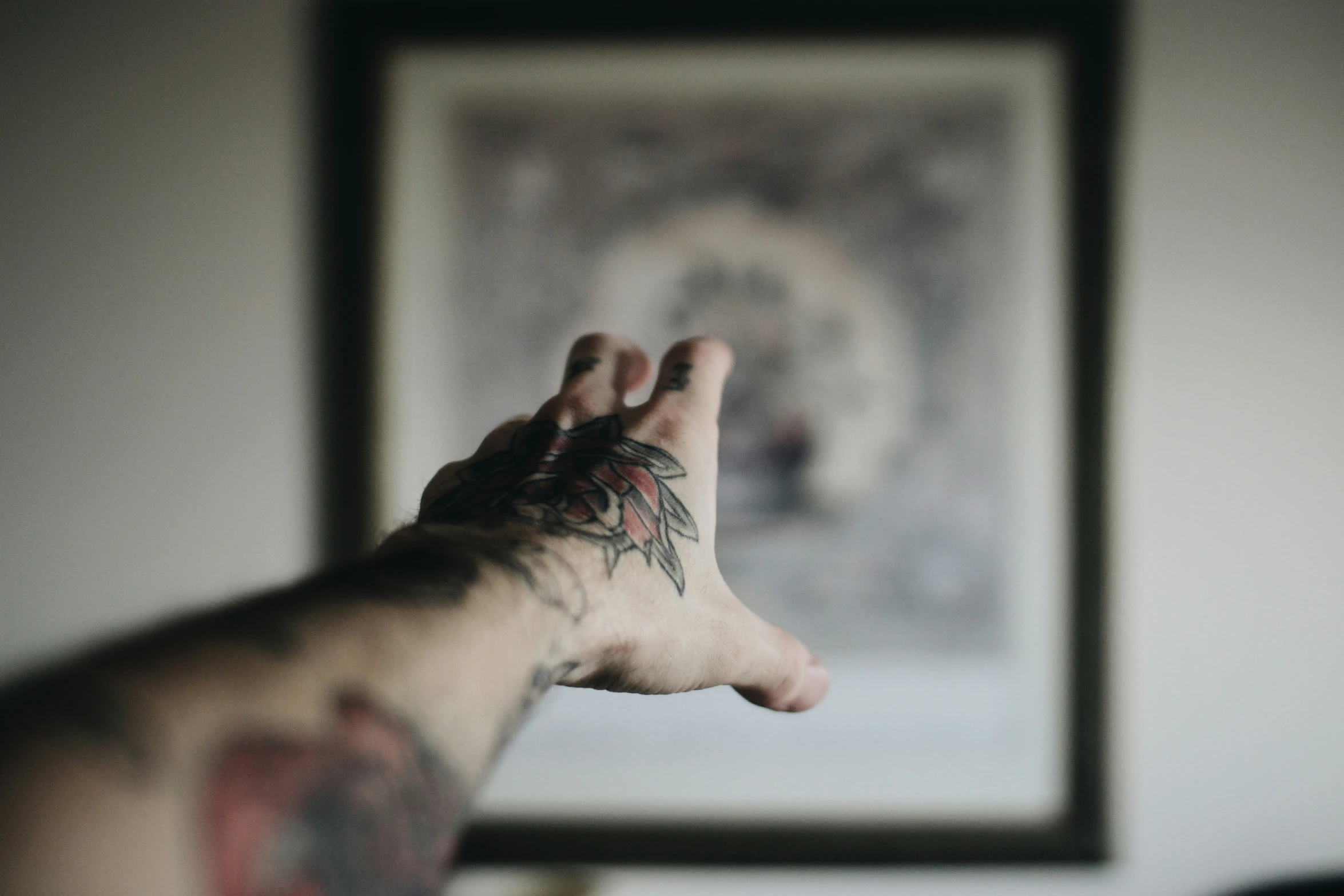 a man with lots of tattoos making a hand signal