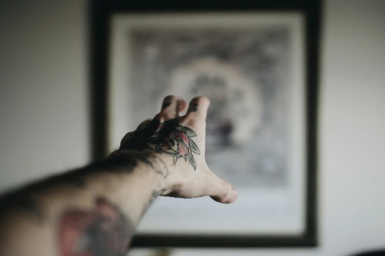 a man with lots of tattoos making a hand signal