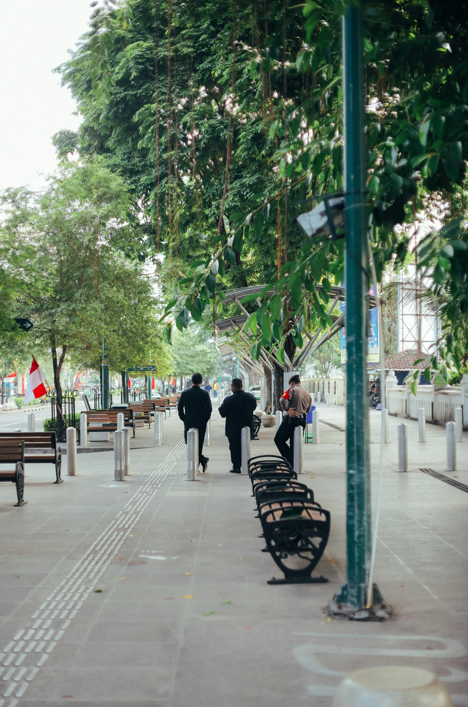 two people walking down the street with benches behind them