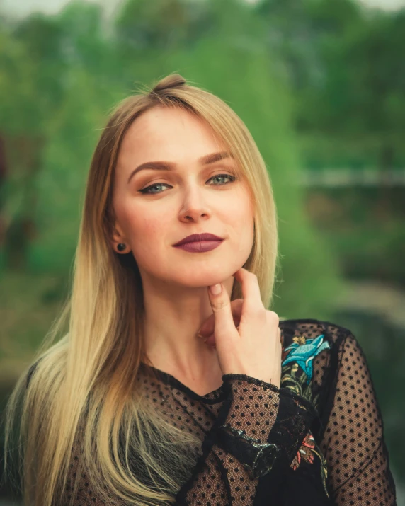 a blonde woman poses in a pose wearing a sheer top