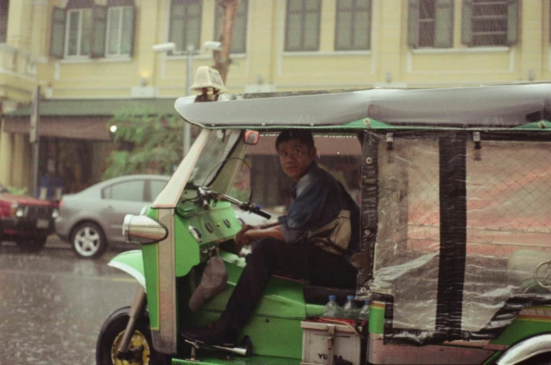 an image of a man riding on the back of a green cart