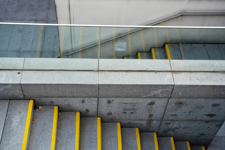 a staircase with no railing that has been made up with concrete and yellow striped hand rails