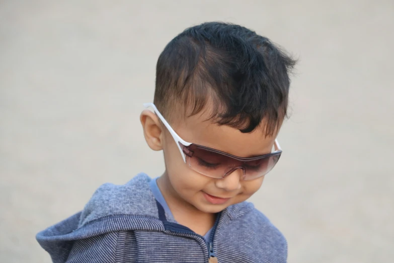 a toddler wearing sunglasses and holding a cellphone