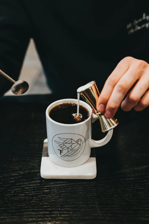 a person in a black shirt pouring liquid into a cup