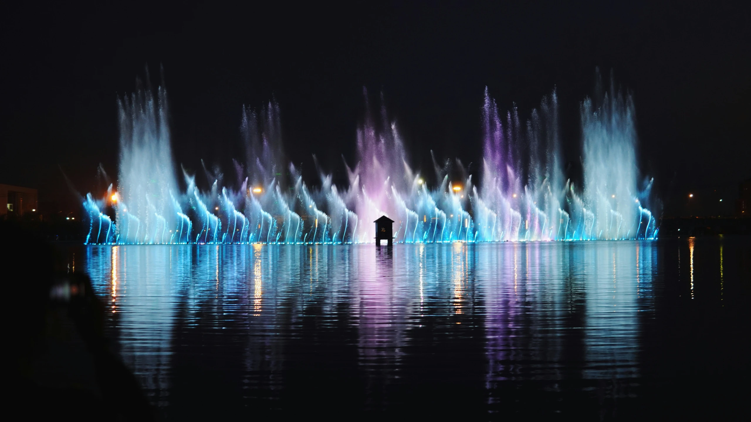 people are standing in front of a fountain of light