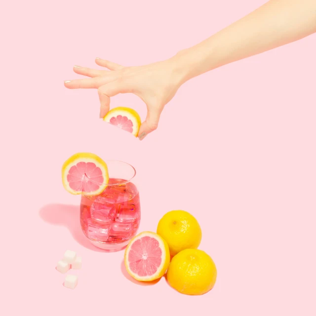 a hand reaches up toward some lemons, and pieces of fruit
