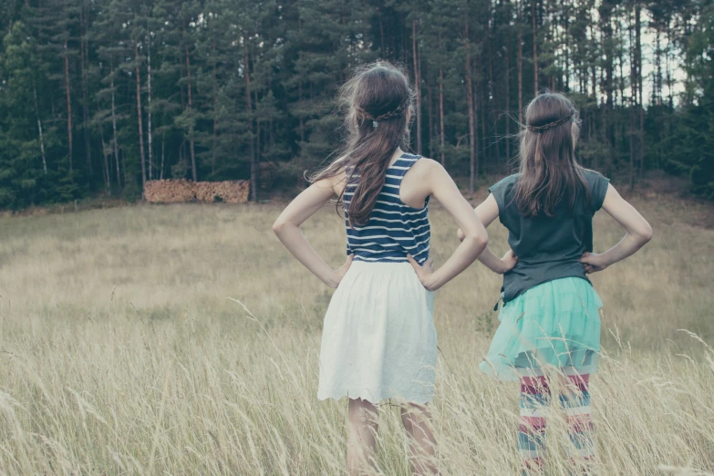 two girls standing in a field looking at trees