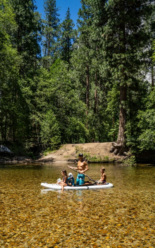 three people on a canoe paddling in the middle of some water