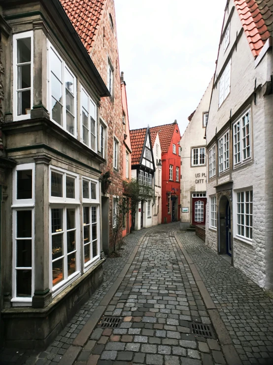 a cobblestone street with several windows and a red tiled roof