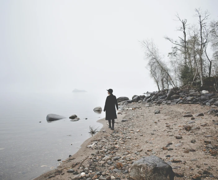 a person walking on a foggy riverbank