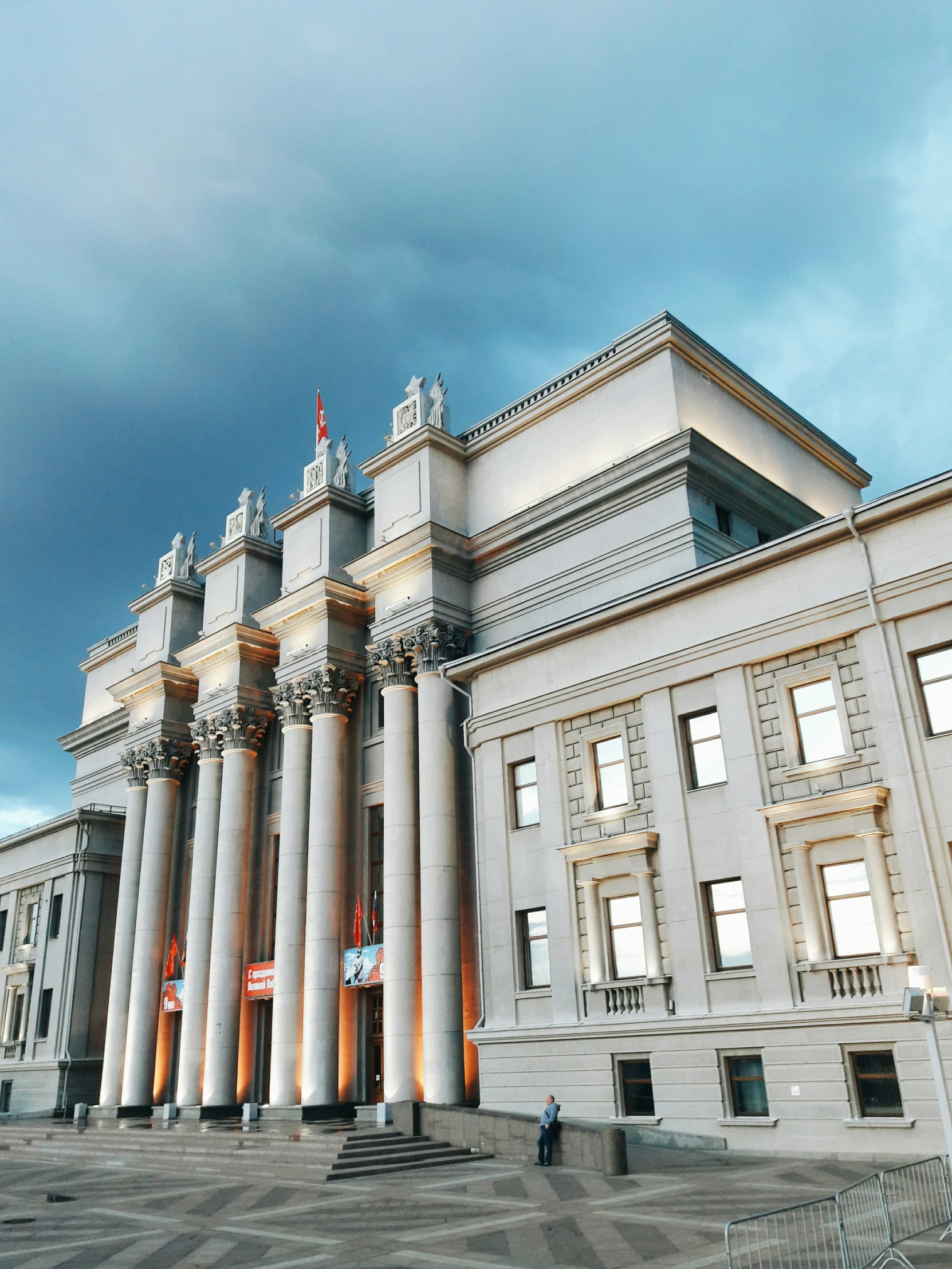 an ornate white building with many pillars stands in front of cloudy skies