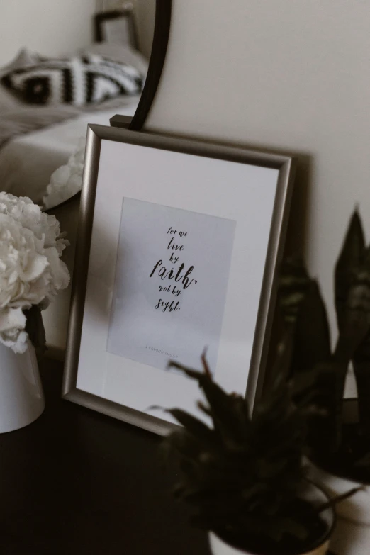 a po frame sits on a table near a vase and some plants