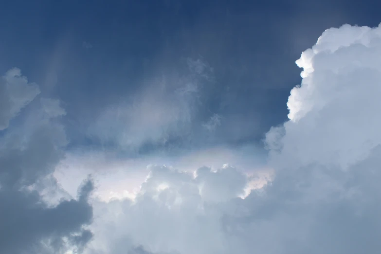 white fluffy clouds against blue sky with a single jet plane in the foreground