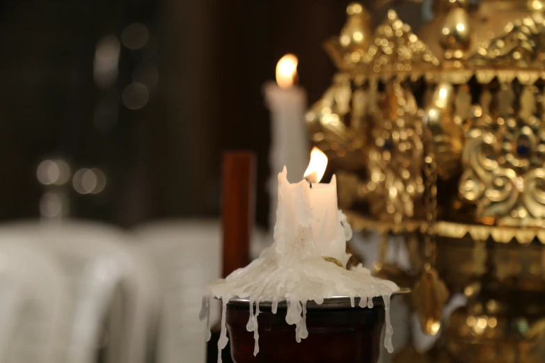 a candle is sitting in a cup next to a golden christmas tree